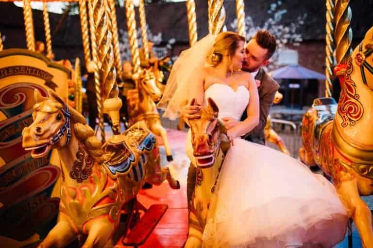 Abby and Andy laughing together on the merry-go-round at their Elsham Hall wedding