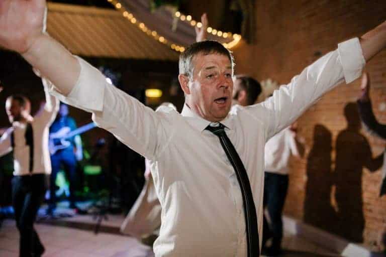 Father of the bride with his arms in the air on the dance floor