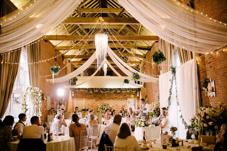 The brick barn at Elsham Hall dressed with draped fabric and fairy lights for a wedding reception