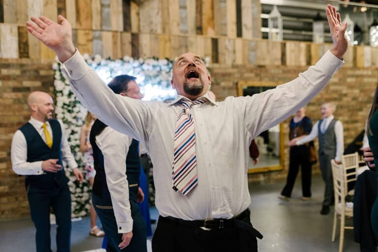 Wedding guest singing with his arms in the air at a winter wedding party at Bunny Hill, North Cliffe