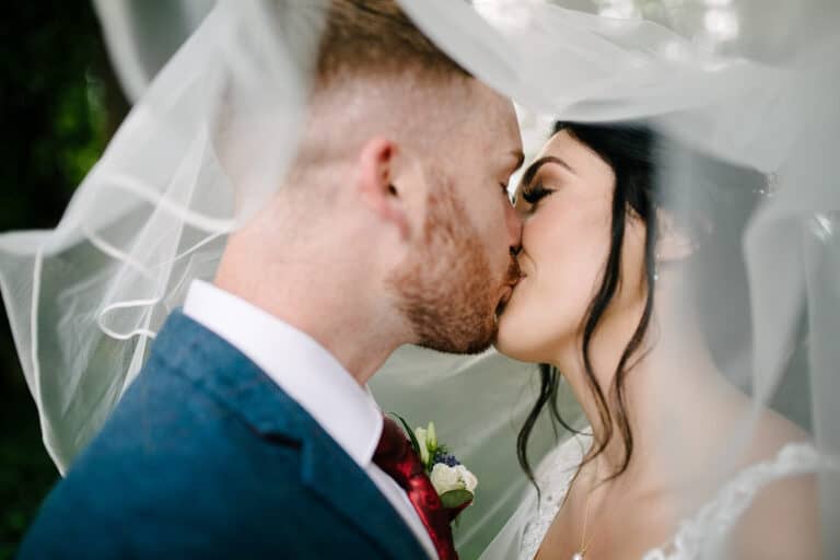 Chloe and Scott kissing beneath her veil on their Elsham Hall wedding day