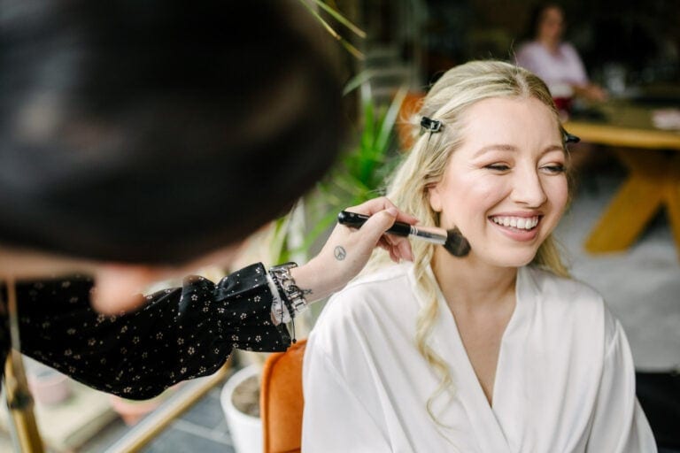 Bride laughing as her make-up is finished on the morning of her Bunny Hill wedding – relaxed bridal prep photography
