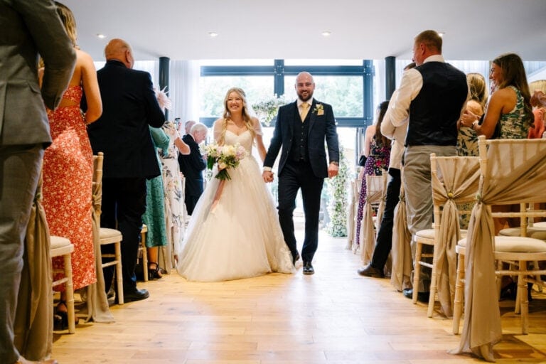 Just married – bride and groom walking back down the aisle in the Garden Room at Bunny Hill, North Cliffe
