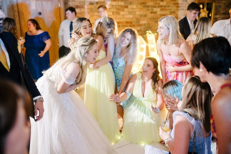 Bride laughing with guests on the barn dance floor – candid evening wedding photography in Yorkshire