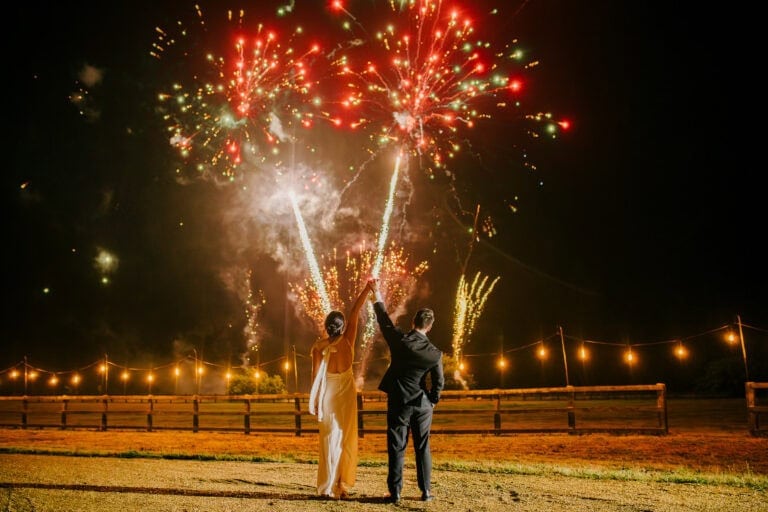 Bride and groom watching fireworks light up the night sky at the end of their wedding day