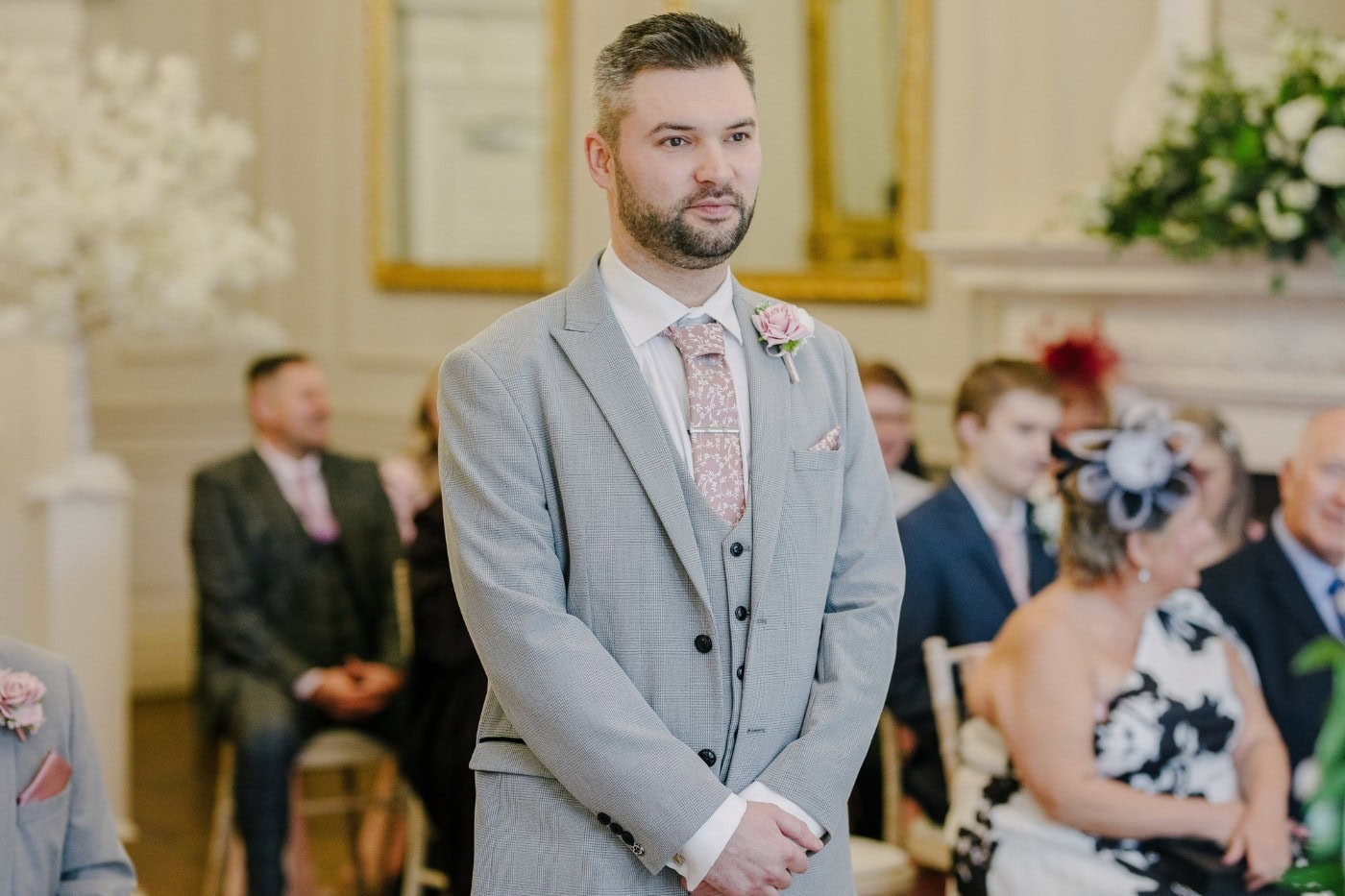The groom waiting nervously at the front of the ceremony room at Bawtry Hall as guests take their seats