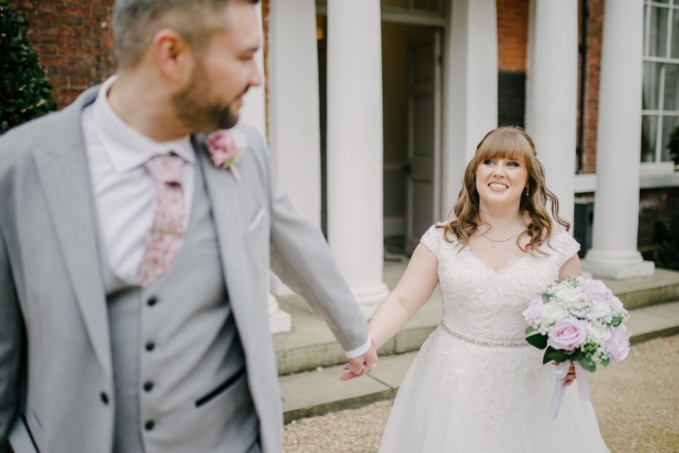 The bride and groom holding hands in front of the Georgian hall near Doncaster