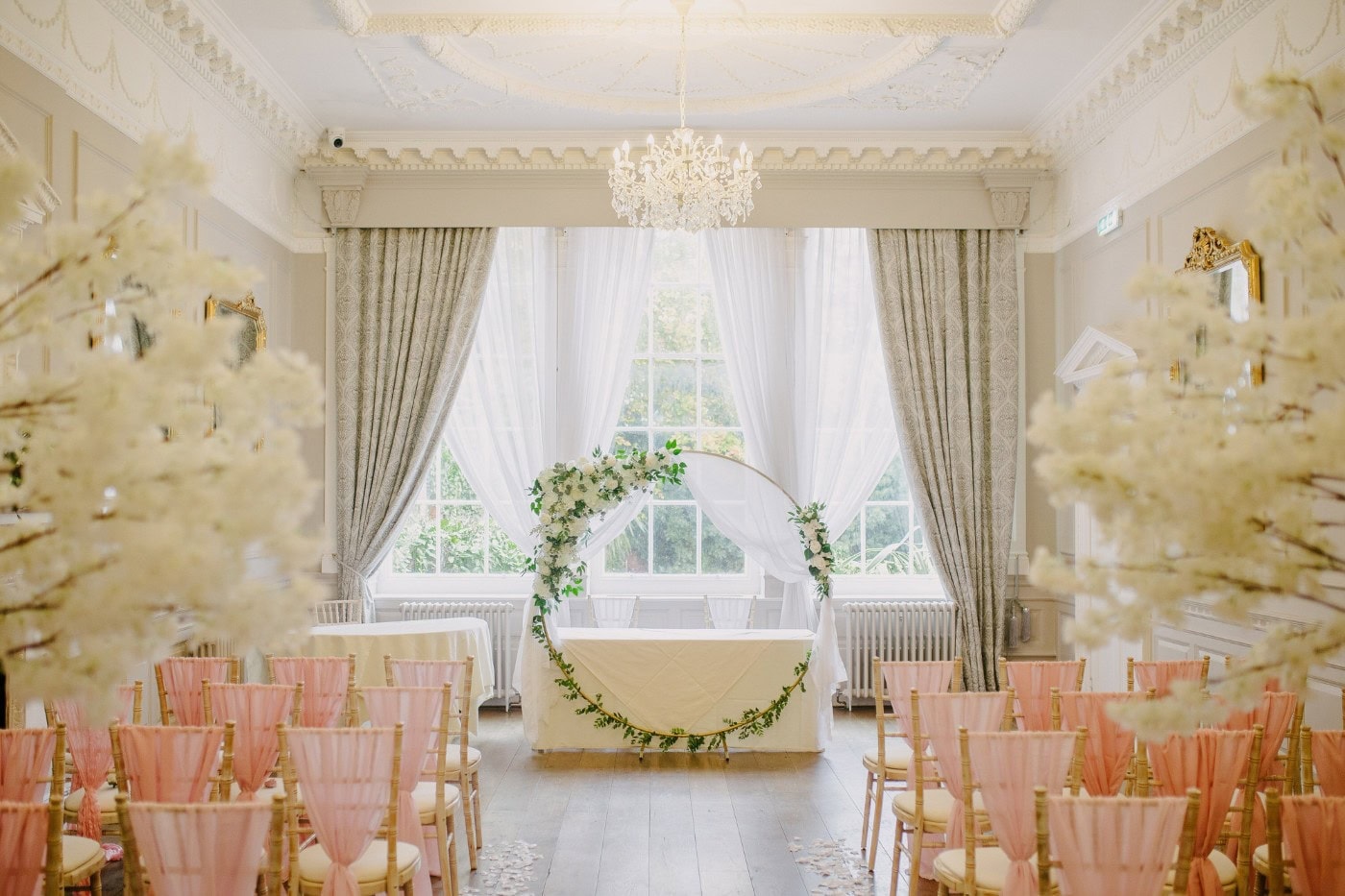 The wedding breakfast room at Bawtry Hall set with white blossom trees and blush pink chairs
