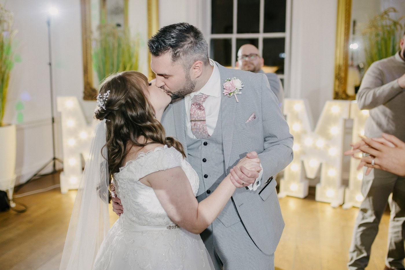 The bride and groom sharing a kiss as they dance in front of the glowing MR & MRS letters at their Bawtry Hall wedding