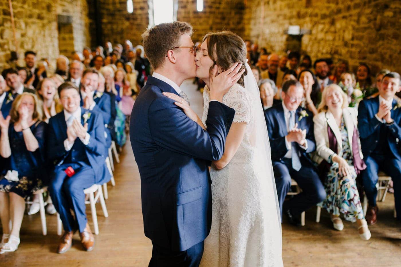 First kiss at the Danby Castle wedding ceremony with family and friends cheering