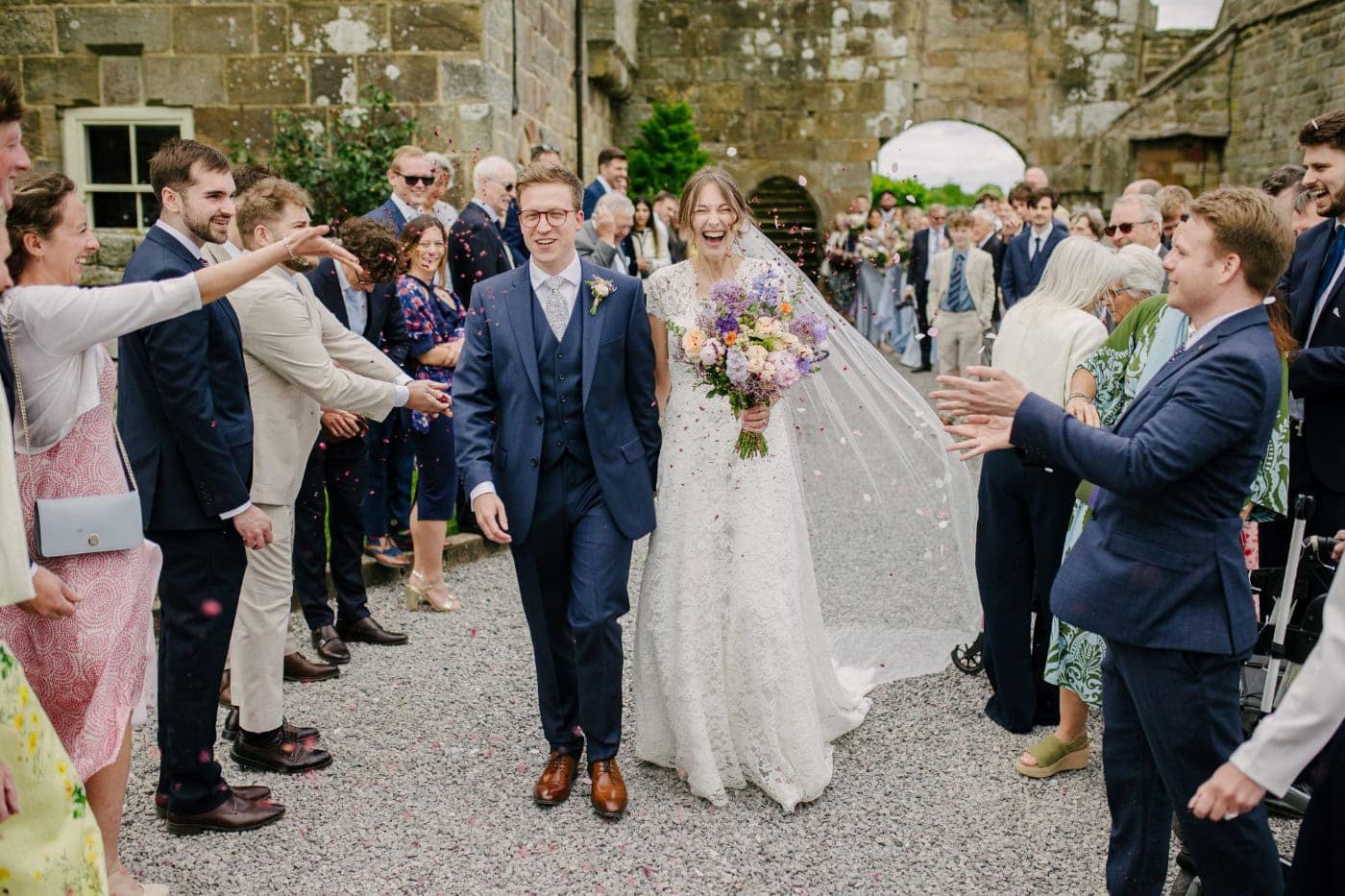 Confetti outside the ruins of Danby Castle after the wedding ceremony on a summer afternoon