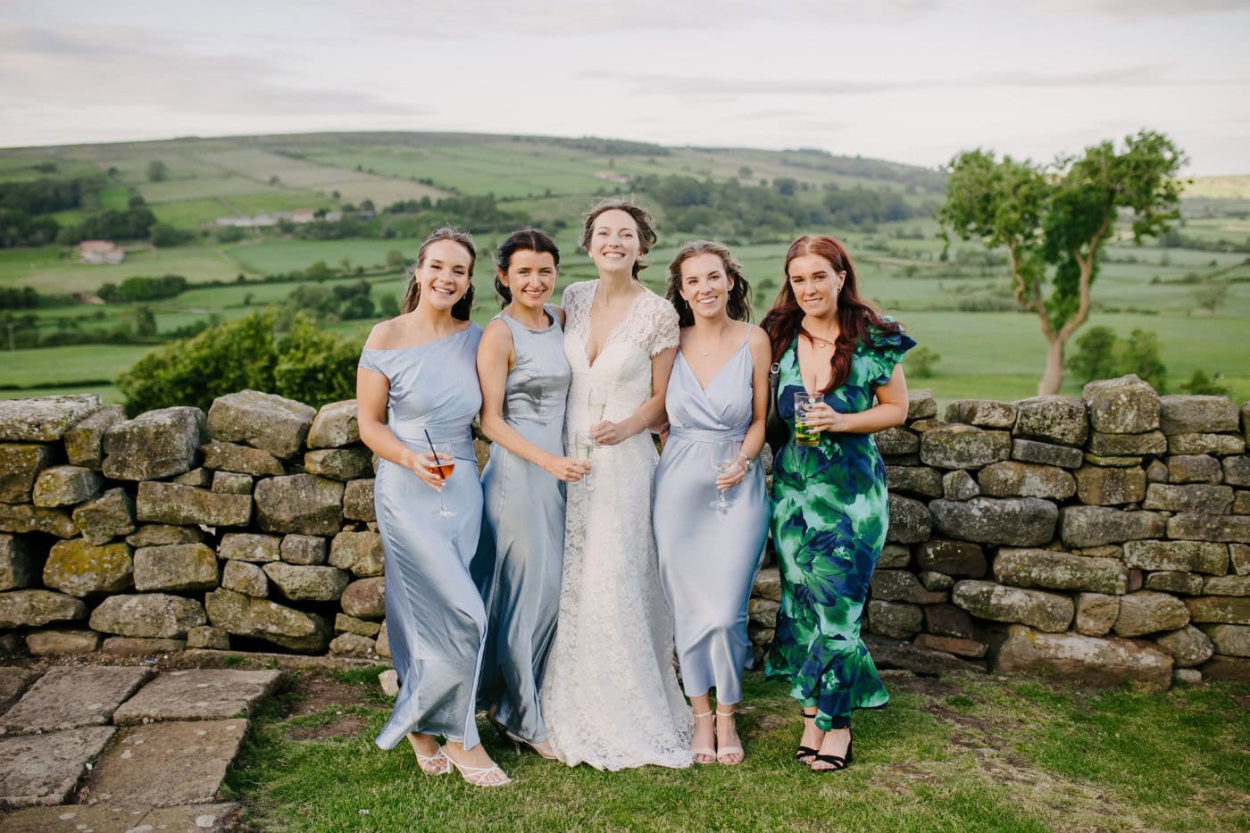 Ellie with her bridesmaids by the dry stone wall in the evening light