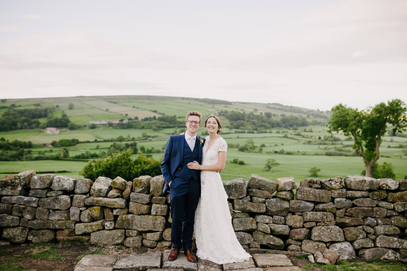 Ellie and George by a dry stone wall at Danby Castle overlooking the Esk Valley at golden hour