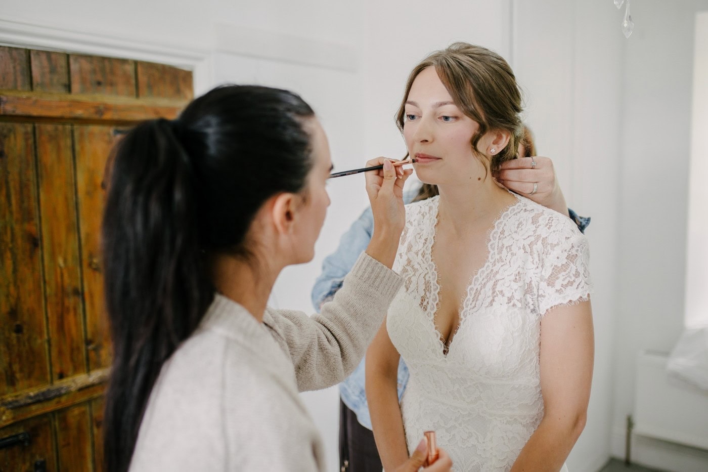 Ellie having her makeup touched up in her lace wedding dress before the ceremony